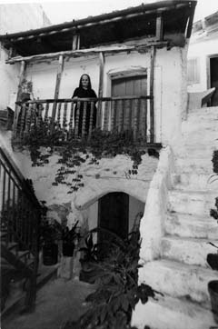 Anziana donna si affaccia dal tipico balcone ligneo di una casa tradizionale (foto Catte)